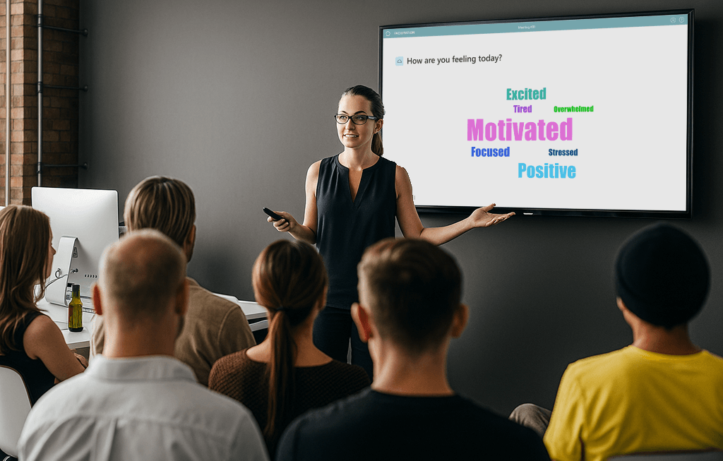 Woman presenting to a seated group with a screen showing a word cloud of feelings including 'Motivated,' 'Positive,' and 'Excited.'